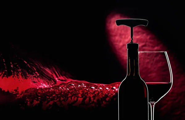 Bottle with corkscrew and glass of red wine on a dark background — 스톡 사진