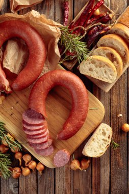 Eski ahşap bir masada ekmek ve baharatla tütsülenmiş sosis..