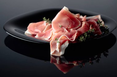 Siyah tabakta kekik olan Prosciutto..