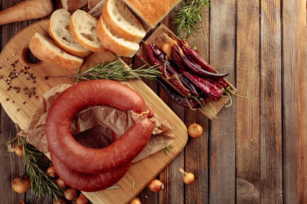 Rökt korv med bröd och kryddor på ett gammalt träbord. — Stockfoto