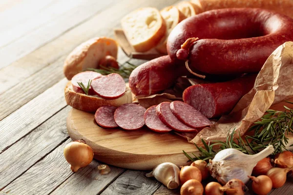 Su un vecchio tavolo di legno salsiccia con pane, rosmarino, cipolla e pe — Foto Stock