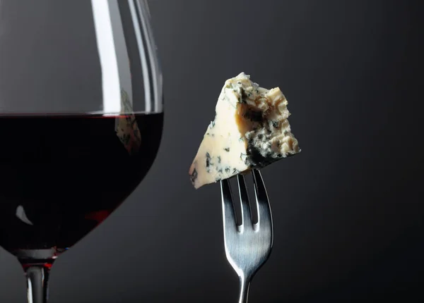 Pedazo de queso azul en un tenedor y vino tinto . — Foto de Stock