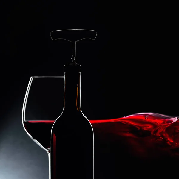 Bouteille avec tire-bouchon et verre de vin rouge sur fond sombre — Photo
