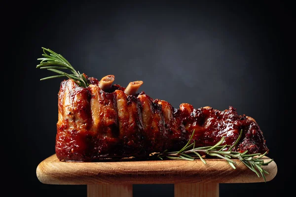 Costillas de cerdo a la parrilla con romero en una tabla de madera . —  Fotos de Stock