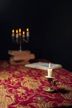 Burning candle on a dark background with the silhouette of the c