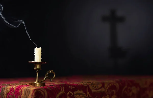 Extinguished candle on a dark background with the silhouette of — Stock Photo, Image