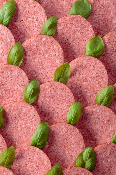 Sliced smoked sausage with green basil leaves. — Stock Photo, Image