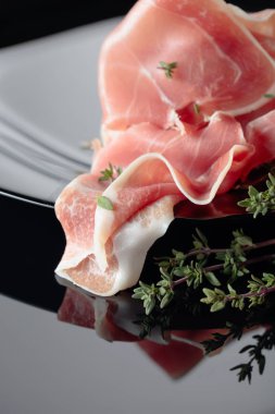 Siyah tabakta kekik olan Prosciutto..