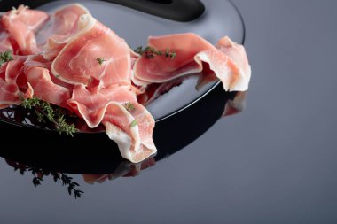Siyah tabakta kekik olan Prosciutto..