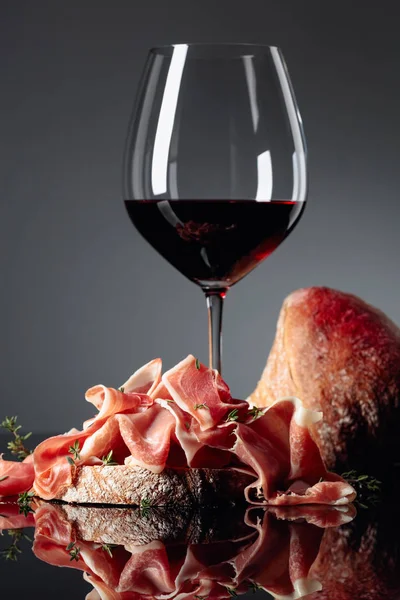 Prosciutto au ciabatta, vin rouge et thym sur fond noir — Photo