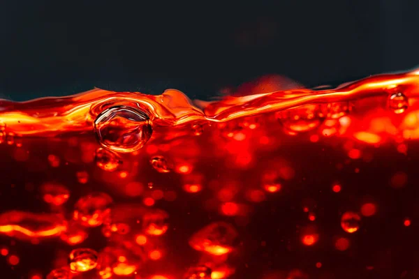 Alcoholic drink on dark background, abstract splashing. — Stock Photo, Image