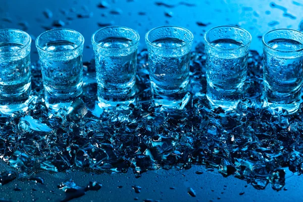 Copos úmidos de vodka com gelo em um fundo reflexivo preto . — Fotografia de Stock