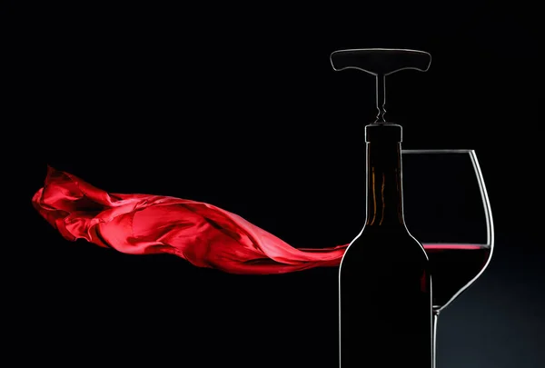 Bottle with corkscrew and glass of red wine on a dark background — 스톡 사진