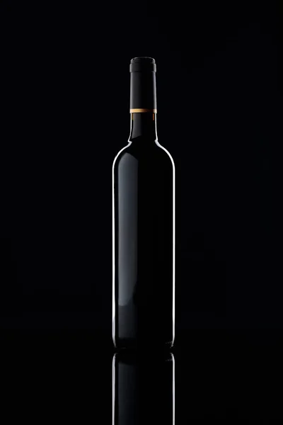 Botella y copa de vino tinto sobre fondo negro. — Foto de Stock