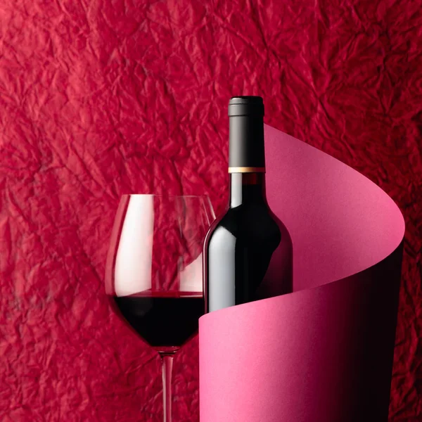 Пляшка червоного вина на червоному тлі. Копіювати простір . — стокове фото