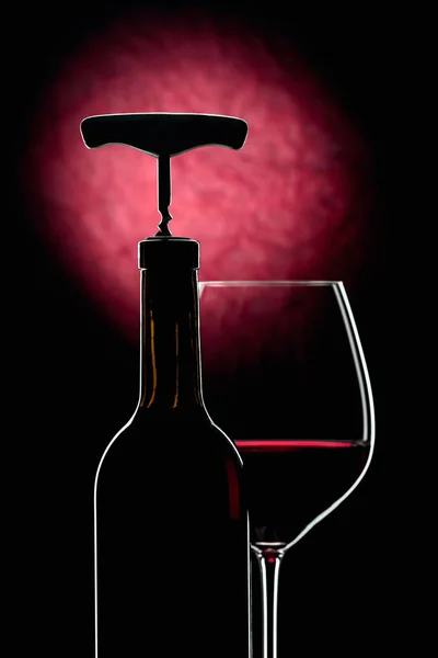 Bouteille et verres de vin rouge sur fond sombre . — Photo