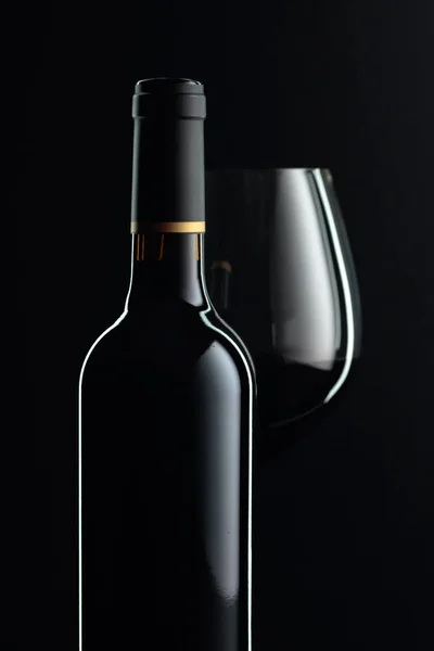 Geschlossene Flasche und ein Glas Rotwein auf schwarzem Hintergrund. — Stockfoto