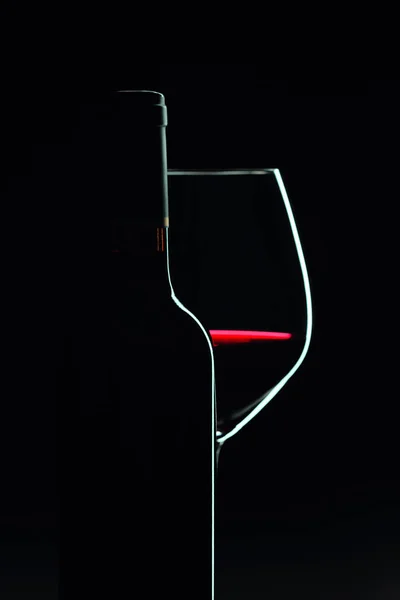 Bottiglia chiusa e bicchiere di vino rosso su fondo nero . — Foto Stock