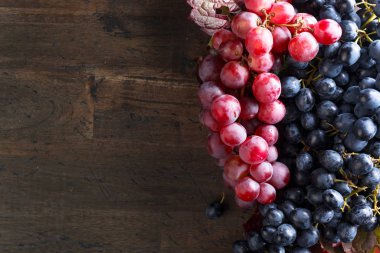 Eski ahşap arka planda yaprakları olan kırmızı ve mavi üzümler.. 
