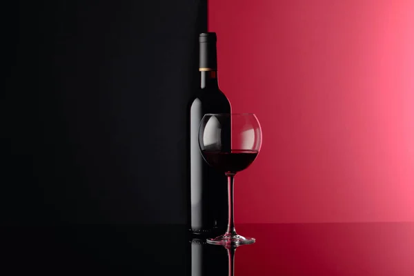 Glas en fles rode wijn op een zwarte reflecterende achtergrond. C — Stockfoto