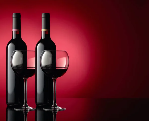 Bicchieri e bottiglie di vino rosso su un tavolo riflettente nero, dar — Foto Stock