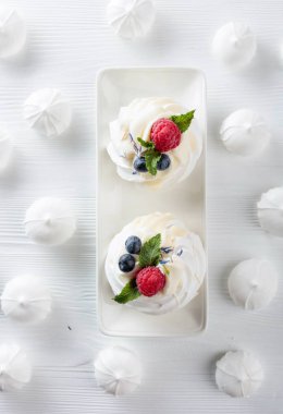 Dessert Pavlova with raspberries, blueberries and mint on a whit clipart