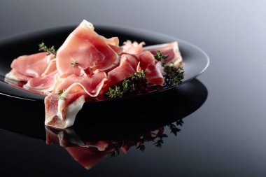 Siyah tabakta kekik olan Prosciutto..