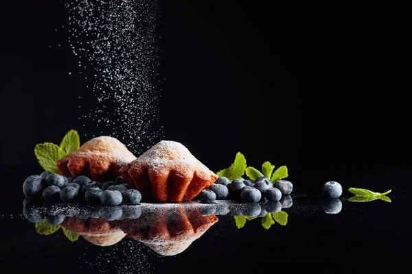 Muffin cosparsi di zucchero in polvere su uno schienale nero riflettente — Foto Stock