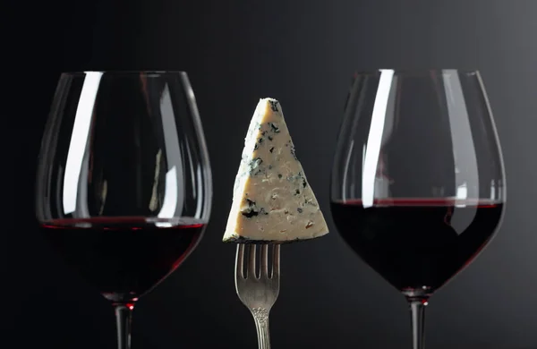 Morceau de fromage bleu sur une fourchette et vin rouge . — Photo