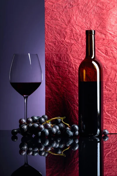 Blå druvor och rött vin på ett svart bord. — Stockfoto