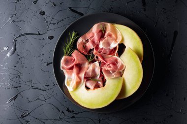 Biberiyeli jambon ve siyah tabakta kavun.. 