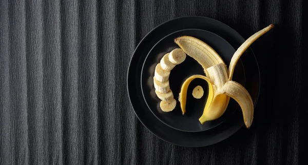 Ripe juicy banana on a black plate. — Stock Photo, Image