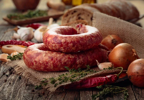 Dry-cured sausage with bread and spices on a old wooden table.