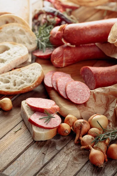 Su un vecchio tavolo di legno salsiccia con pane, rosmarino, cipolla e pe — Foto Stock