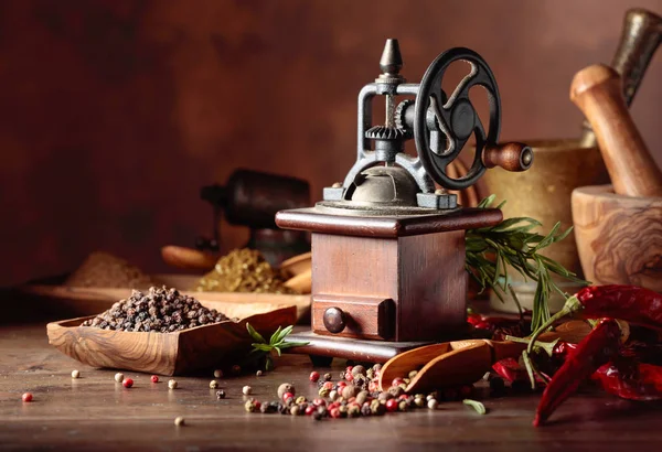 Molino de pimienta vintage con utensilios de cocina, especias y romero o — Foto de Stock