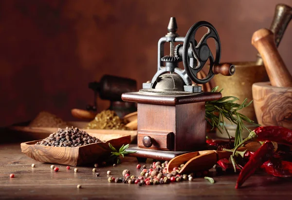 Vintage pepper mill with kitchen utensils, spices and rosemary o