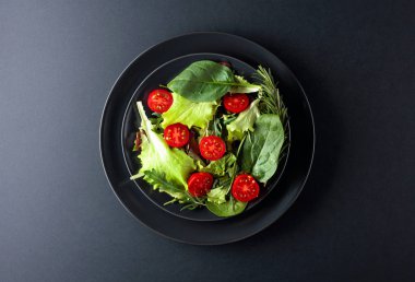 Siyah arka planda vişneli domatesli taze karışık salata. Buraya...