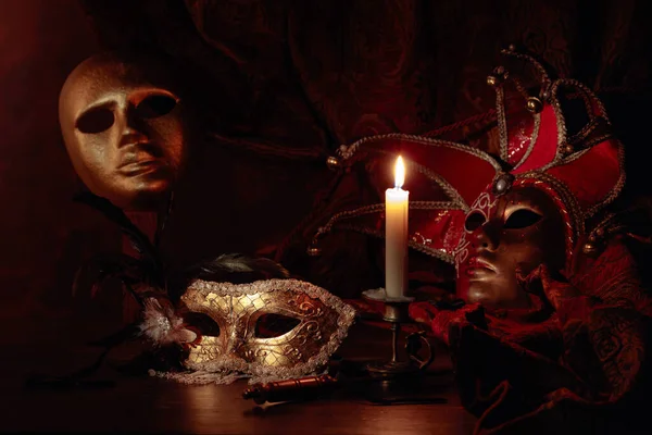 Máscaras de carnaval e pequeno castiçal de bronze com vela ardente . — Fotografia de Stock
