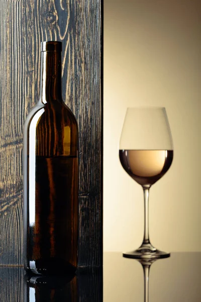 Fles en glas witte wijn op een zwarte tafel. — Stockfoto