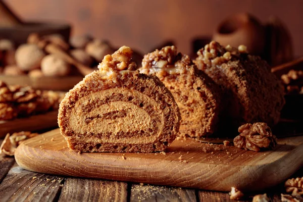 Walnut cake, nuts and wooden kitchen utensils on a wooden table. — Stock Photo, Image