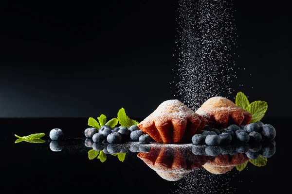 Muffins polvilhados com açúcar em pó em um backgr reflexivo preto — Fotografia de Stock