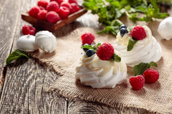 Dessert pavlova mit Himbeeren, Blaubeeren und Minze auf einem alten — Stockfoto