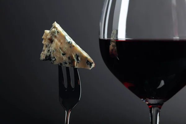 Pedazo de queso azul en un tenedor y vino tinto . — Foto de Stock