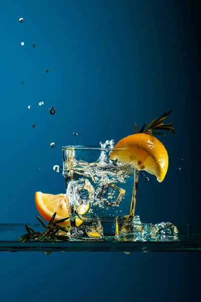 Cocktail gin-tonic with lemon and rosemary on a glass table. — Stock Photo, Image