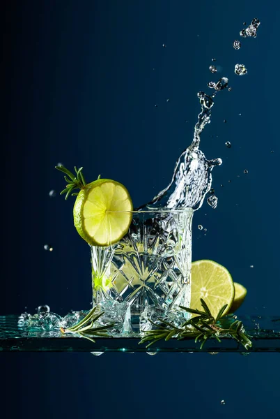 Cocktail gin-tonic with lime and rosemary on a glass table. — Stock Photo, Image