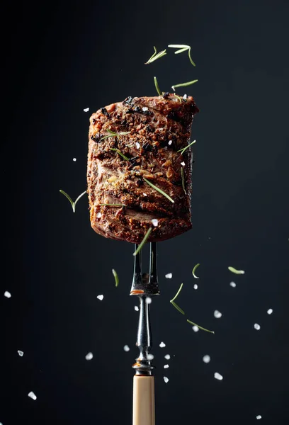 Beef steak on a fork sprinkled with rosemary and sea salt. — Stock Photo, Image