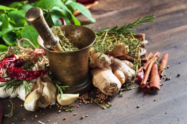  Eski pirinç havan, eski ahşap bir masada bitkiler ve baharatlar..