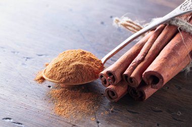 Tarçın çubukları ve ahşap bir masada tarçın tozu ile kaşık..