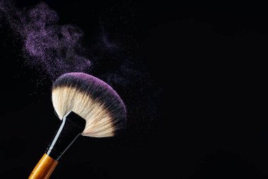Siyah arka planda parlak mor göz farı olan profesyonel makyaj fırçası konsepti. Boşluğu kopyala.