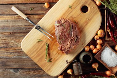 Baharatlı soslu pişirilmemiş biftek eski ahşap bir masada biberiye. Üst görünüm.